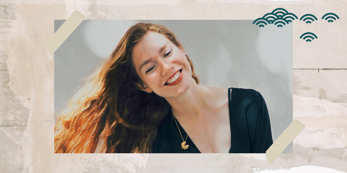 A girl with red hair smiling while wearing our Signature Fortune Cookie Locket in gold.